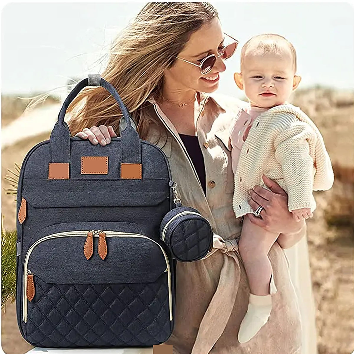 Parent holding a baby next to the navy diaper backpack