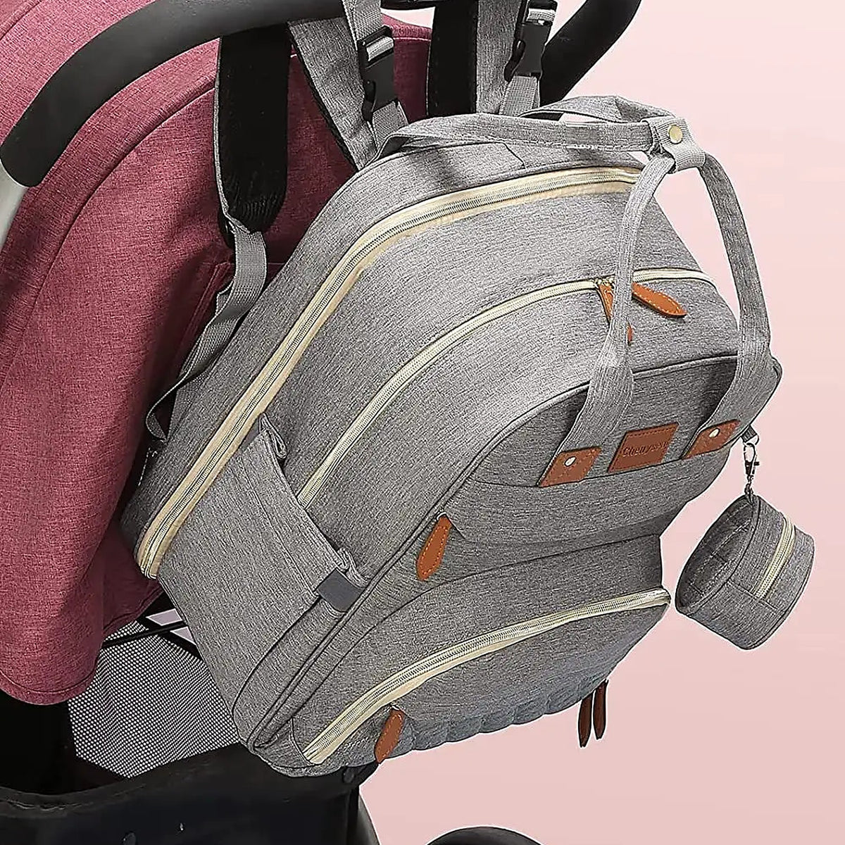 Gray diaper backpack hanging from a stroller handle